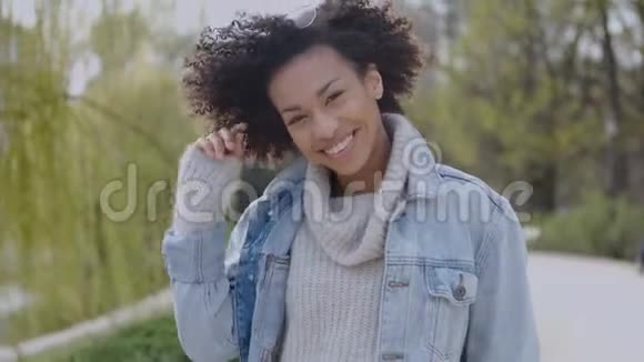 快乐和微笑的混血女孩带着非洲发型在公园散步视频的预览图