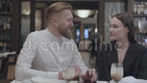 成熟的男人在餐厅的桌子上给一个漂亮的年轻女人讲故事视频的预览图