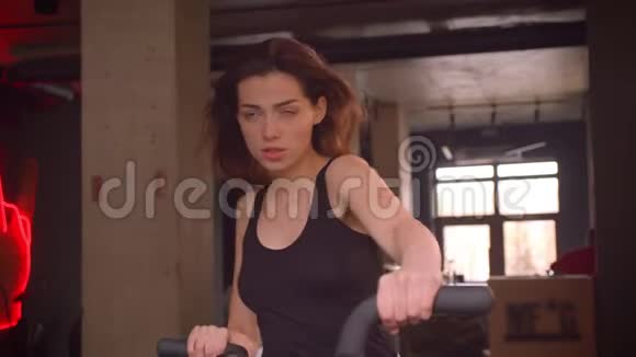 一位年轻有魅力的运动员的特写镜头一位长头发的女性在室内健身房的轨道上工作视频的预览图