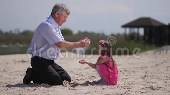 女孩和祖父在海滩上他们玩沙子4K慢慢视频的预览图