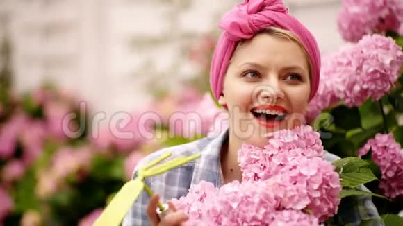 微笑的女孩有着粉红色的大花蕾快乐的女人花匠护花和浇水妇女护理视频的预览图