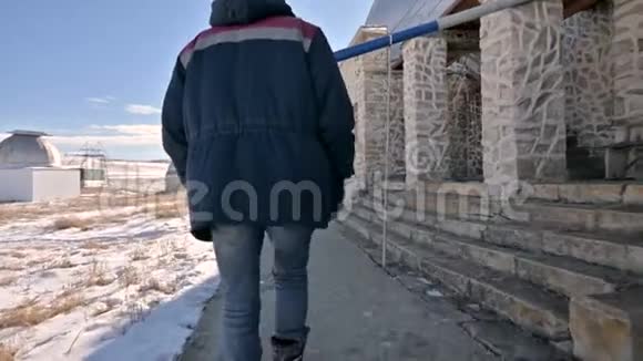 一位穿着牛仔裤和保暖制服的男性研究员在冬天阳光明媚的白天在雪地里行走视频的预览图