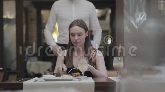 一个美丽的年轻女孩在咖啡馆或餐馆吃饭的肖像一个长着胡子的男人或丈夫走到后面关上门视频的预览图