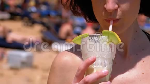 夏天小女孩在沙滩上喝着来自试管的异国鸡尾酒视频的预览图