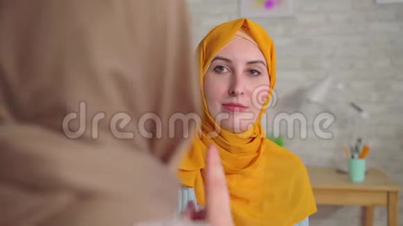 两个戴着头巾的年轻穆斯林美女在房子附近的客厅里用手语交谈视频的预览图