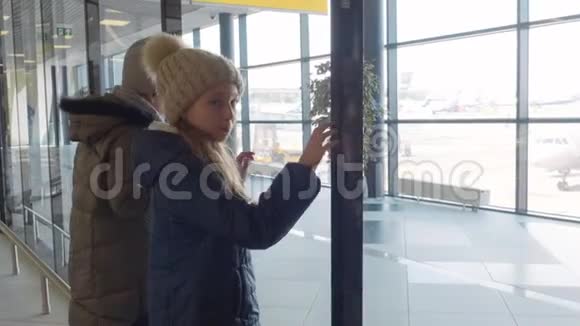 十几岁的女孩正在等待他们的航班看着机场航站楼的全景窗口视频的预览图