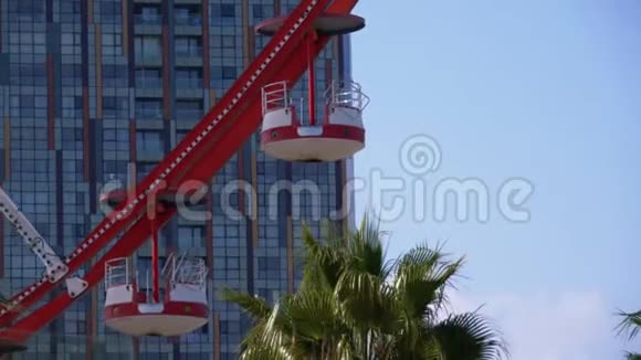 摩天轮舱或胶囊旋转与现代摩天大楼和棕榈树在度假城镇阳光明媚的一天视频的预览图