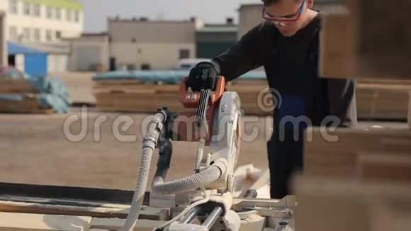 工人佩戴施工护目镜黑色和蓝色制服使用木材切割机人切木木板视频的预览图