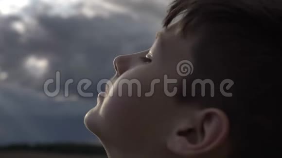 快乐的男孩在傍晚的大风天气看天空特写视频的预览图