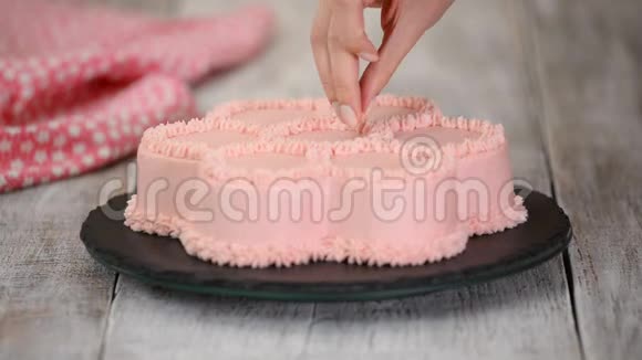 糕点厨师是装饰一个粉红色的蛋糕形状的花系列视频的预览图