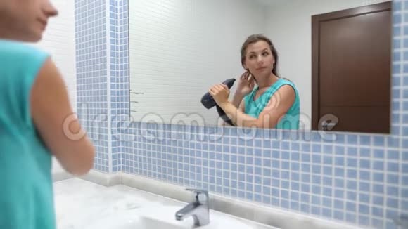 漂亮女人在浴室镜子前吹头发视频的预览图