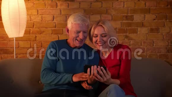 在一间舒适的公寓里坐在沙发上的一对高级幸福夫妇在电话里打视频的特写镜头视频的预览图