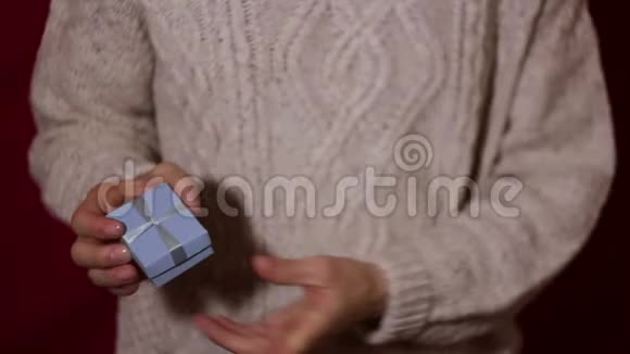 漂亮的女孩在一个蓝色的小盒子里扭着手里的礼物美丽的女性手拿着一个带礼物的蓝色小盒子视频的预览图
