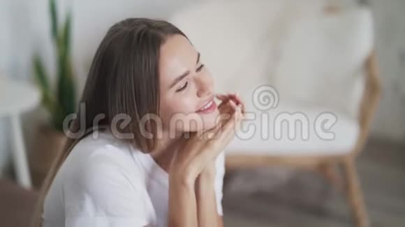 美丽的年轻女子坐在床上看着相机微笑着的肖像视频的预览图