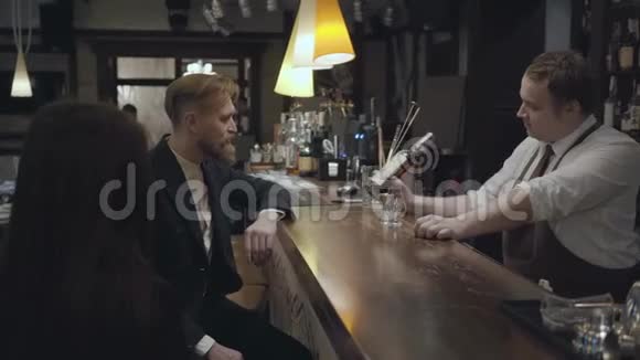 一个有经验的侍者站在一家昂贵的餐馆或酒吧的酒吧后面给一个年轻人提供一种很好的威士忌视频的预览图