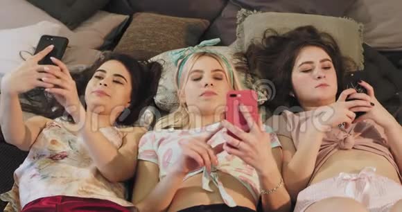 一群朋友躺在床上用智能手机发短信边吃边吃视频的预览图