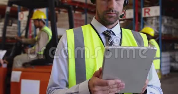 男性仓库管理员使用耳机和平板电脑视频的预览图