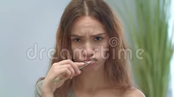 美丽的女人用牙刷和牙膏前置摄像头刷牙视频的预览图