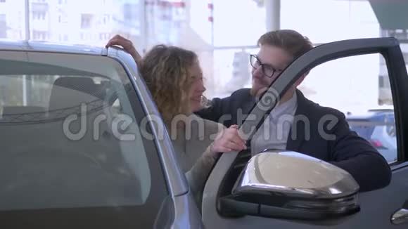 汽车购买幸福的夫妻在爱的车主高兴购买显示钥匙在汽车销售中心视频的预览图