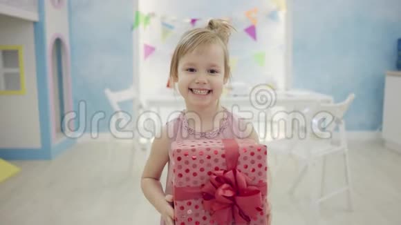 小女孩手里拿着生日礼物在镜头前微笑视频的预览图