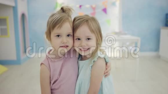 两个漂亮的小女孩竖起大拇指互相拥抱站在镜头前视频的预览图