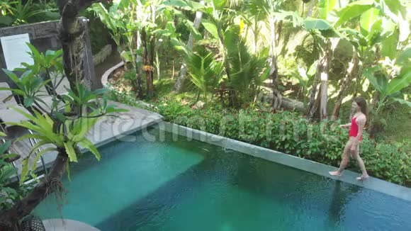 带热带花园的别墅无限游泳池鸟瞰图女人走在池边欣赏丛林风光视频的预览图