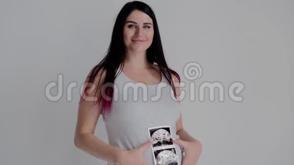 穿灰色衬衫的孕妇摆姿势母亲的肖像与婴儿的扫描视频的预览图
