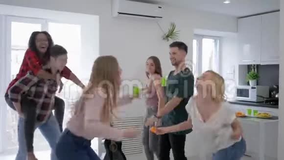 快乐的年轻男女在家庭聚会上手里拿着塑料杯跳舞视频的预览图