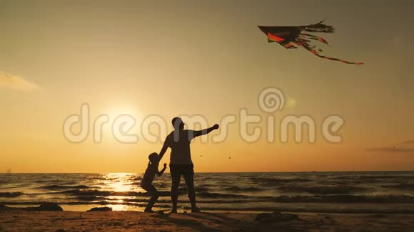 幸福的家庭父亲和孩子女儿在日落时在海滩上放风筝有趣的家庭时光友好家庭的概念视频的预览图