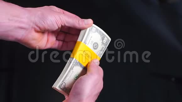 一个商人拿着一捆百美元的钞票视频的预览图