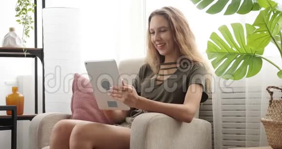 快乐少女使用数码平板电脑扶手椅视频的预览图