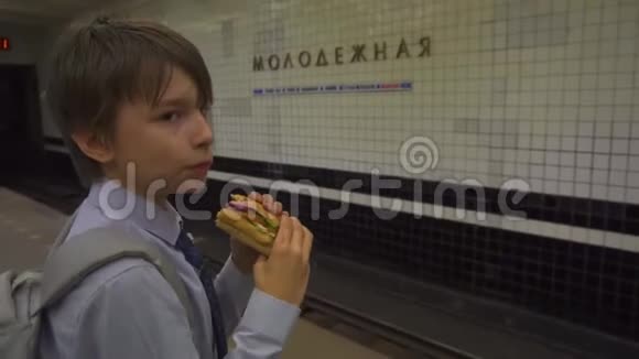年轻人在地铁站台上吃三明治等火车视频的预览图