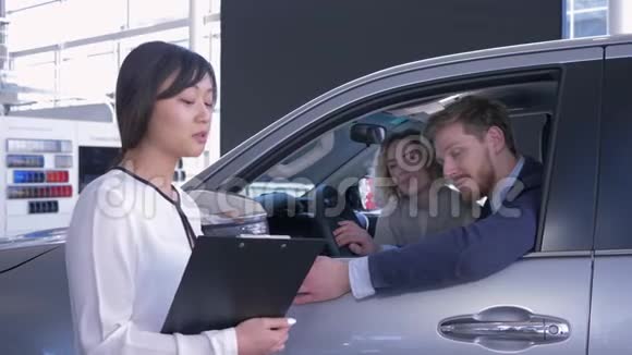 女售货员与家庭伴侣客户的肖像在销售中心购买汽车时显示车内钥匙视频的预览图