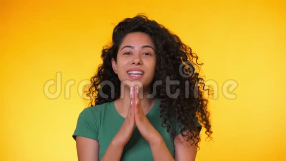 漂亮的西班牙女人穿着绿色t恤在黄色背景下祈祷混血女孩乞求视频的预览图