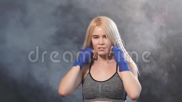 漂亮的女拳击手在蓝色的手包准备了大的战斗与烟雾背景视频的预览图