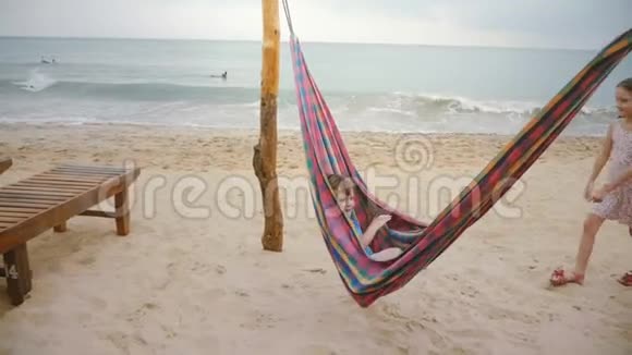 小男孩躺在海滩吊床上在惊人的海岸与可爱的小女孩兄弟姐妹度假视频的预览图