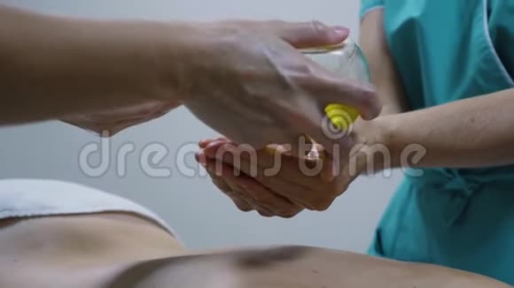 按摩治疗前用女性手在瓶子中特写油视频的预览图