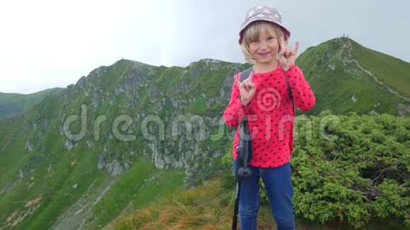 山顶上的小女孩显示出摇滚的手指视频的预览图