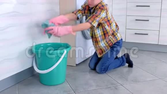 穿橡胶手套的男孩在厨房里洗地板玩布儿童的家庭责任视频的预览图