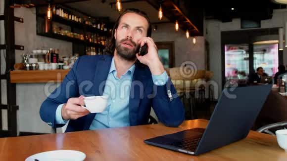 一个年轻的商人用电话坐在咖啡馆的一张桌子旁成功人士日常生活视频的预览图