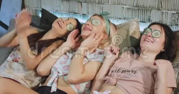 晚上三位女士穿着睡衣在家享受水疗放松的时光她们为脸部制作面具享受时光视频的预览图