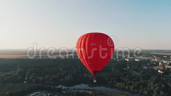 早晨一个美丽的红色气球飞过河流和城市视频的预览图