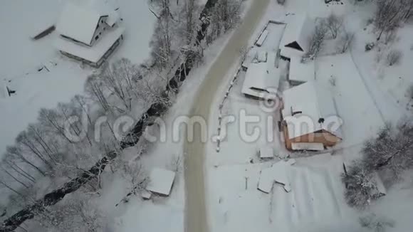 飞越喀尔巴阡山脉的一个村庄和它旁边的一个滑雪胜地沿着河流和房屋的冬季空中道路视频的预览图