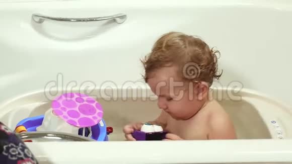 那孩子和妈妈在浴室洗澡玩玩具一个蓝眼睛的婴儿头发是金色的带玩具视频的预览图