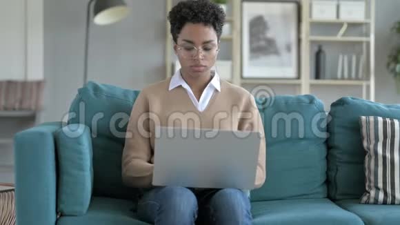 年轻的非洲女孩在沙发上用笔记本电脑视频的预览图