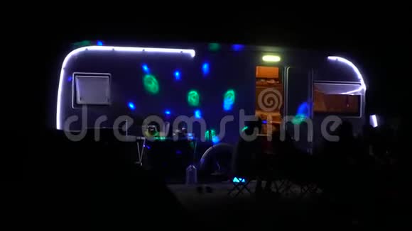 人们晚上坐在拖车附近派对的灯光闪闪发光视频的预览图