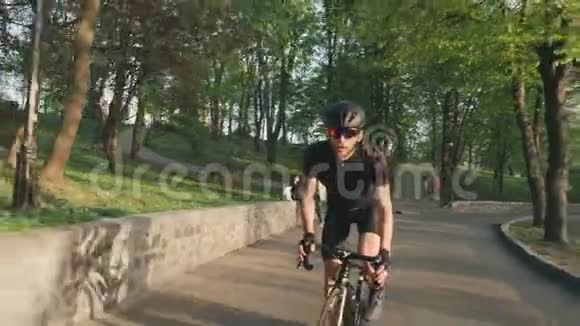 穿着黑色运动服戴着眼镜和头盔骑在我们的马鞍上的强壮的自行车运动员专业自行车运动员视频的预览图