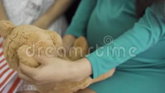 柔软的黄色泰迪熊的特写女性手拿着礼物穿丝绸蓝绿色连衣裙的孕妇视频的预览图
