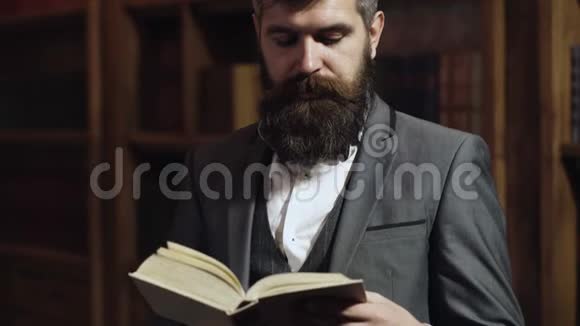 有胡子的人在书架背景上看书智慧精英和教育理念男人花时间视频的预览图