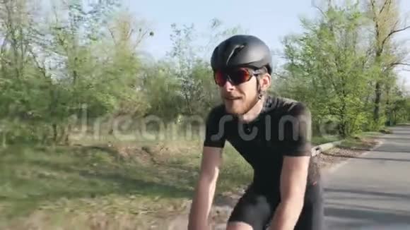 快乐快乐的骑车人在公园骑自行车时微笑骑自行车的人戴着黑色的头盔和太阳镜自行车的概念奴隶视频的预览图